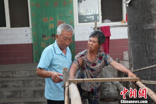 為讓妻子慢慢學會走路，李文生每天扶著妻子一遍一遍練習走路?！±钤杭t 攝