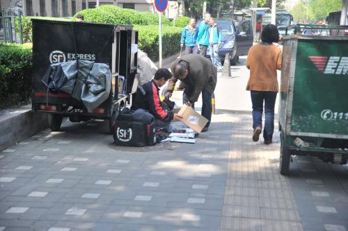 圖為快遞小哥在路邊配送快遞。呂春榮 攝