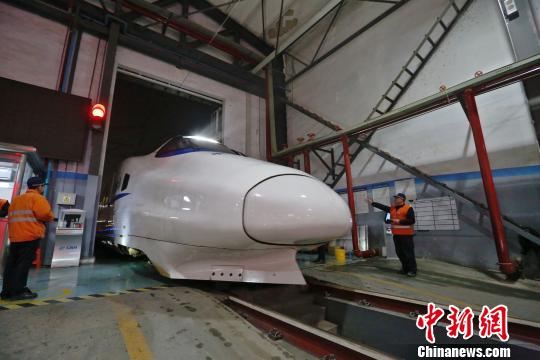 一列動(dòng)車組駛?cè)胲噹欤瑱C(jī)械師位列兩邊檢查車體外觀?！《〔?攝