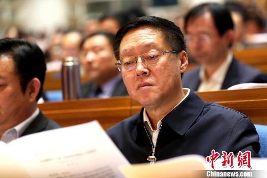 圖為與會政協(xié)委員在現(xiàn)場閱讀會議文件。　梁犇 攝